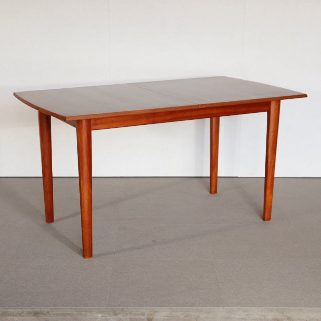 Mid-century British dining table in vintage teak with smooth rectangular top and tapered legs, showcasing natural wood grain .