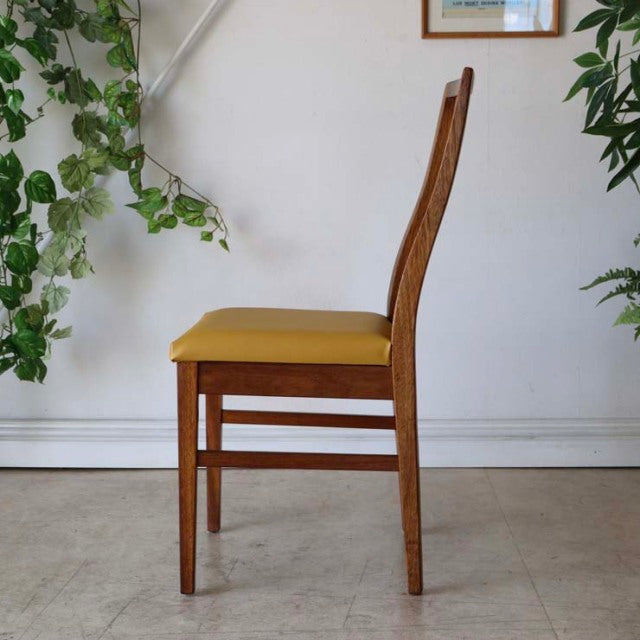 Vintage teak dining chair from British mid-century Denmark collection with yellow seat cushion, elegant wood grain, and.