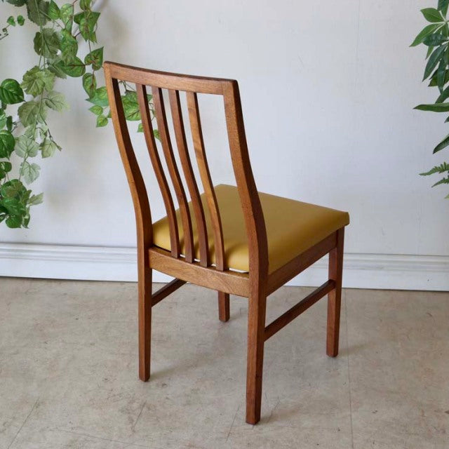 Set of four vintage British mid-century teak dining chairs with yellow upholstered seats and vertical slat backs.