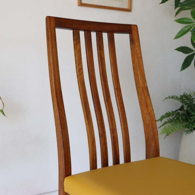 Mid-century British vintage teak dining chair with curved slatted back and vibrant yellow seat cushion.