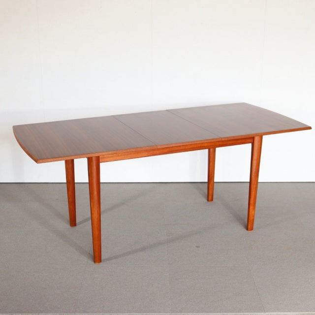 Vintage mid-century teak dining table with rectangular top, smooth wood grain, and slender tapered legs, showcasing British.