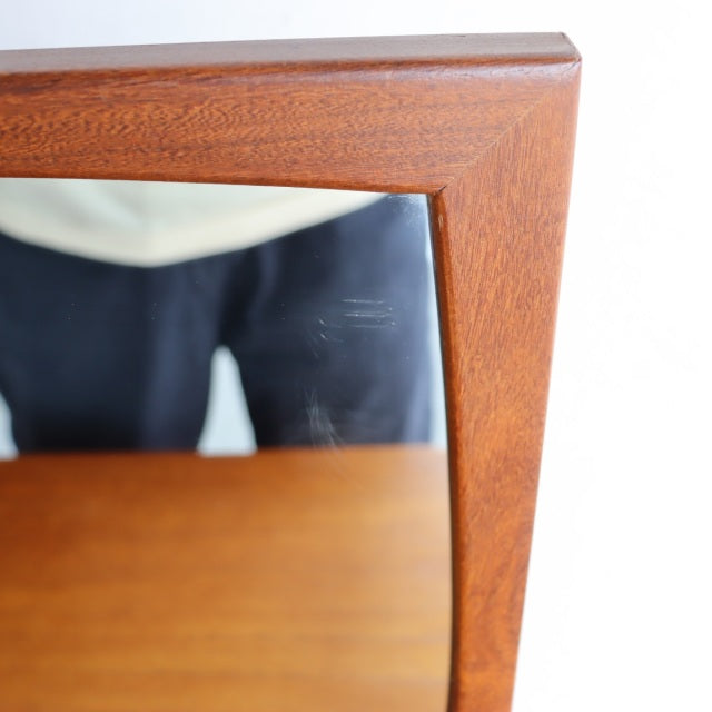 Close-up of vintage teak dresser mirror corner with visible wood grain and mid-century British-Denmark design.