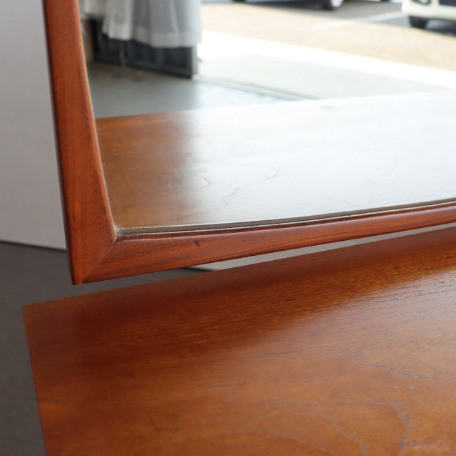 Close-up of vintage mid-century teak dresser with smooth wood grain and angled British-Danish style frame.