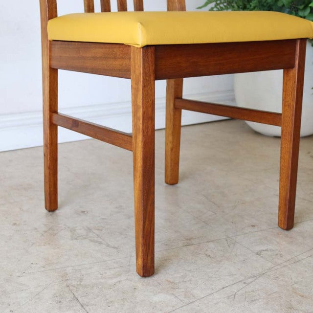 Mid-century British vintage teak dining chair with yellow upholstered seat and clean wooden legs.