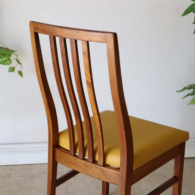 Set of four vintage British mid-century teak dining chairs with yellow upholstered seats and slatted backs.