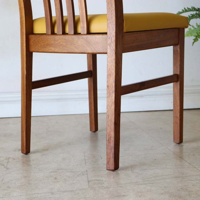 Mid-century British vintage teak dining chair with yellow upholstered seat and vertical slat backrest.