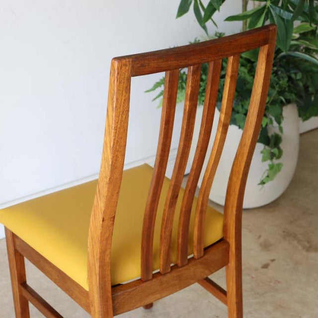 Mid-century British vintage teak dining chair with curved slat back and yellow upholstered seat in good condition.