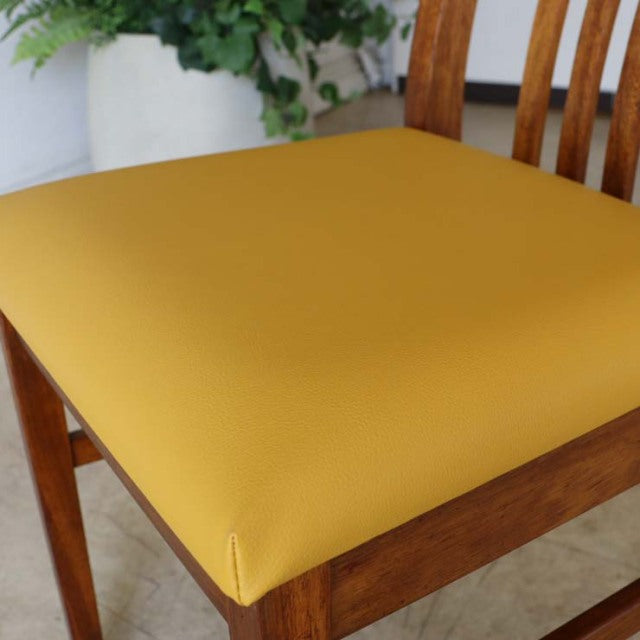 Mid-century British vintage teak dining chair with yellow seat cushion and curved slatted backrest.