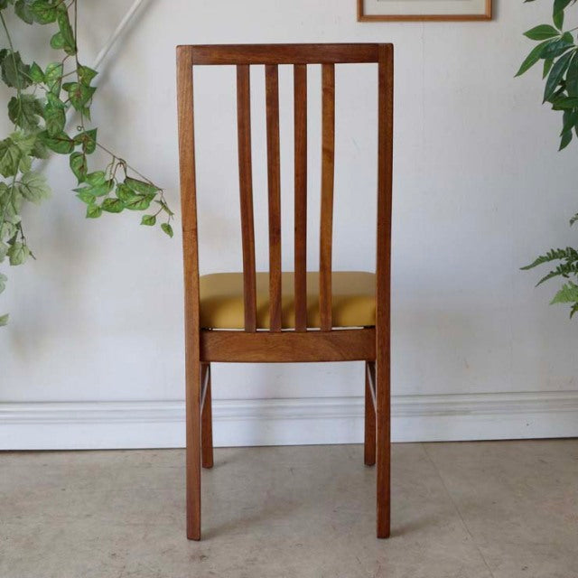 Mid-century British vintage teak dining chair with vertical slat back and yellow seat cushion.