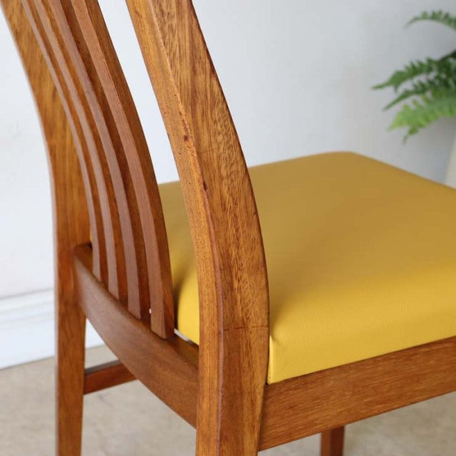 Vintage British mid-century teak dining chair with curved slatted back and vibrant yellow seat cushion.