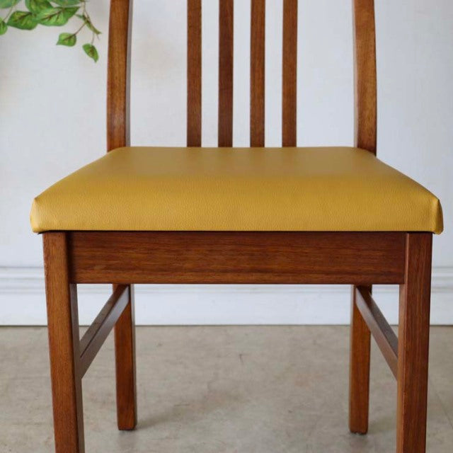 Vintage British mid-century teak dining chair with yellow seat cushion and vertical slat backrest.