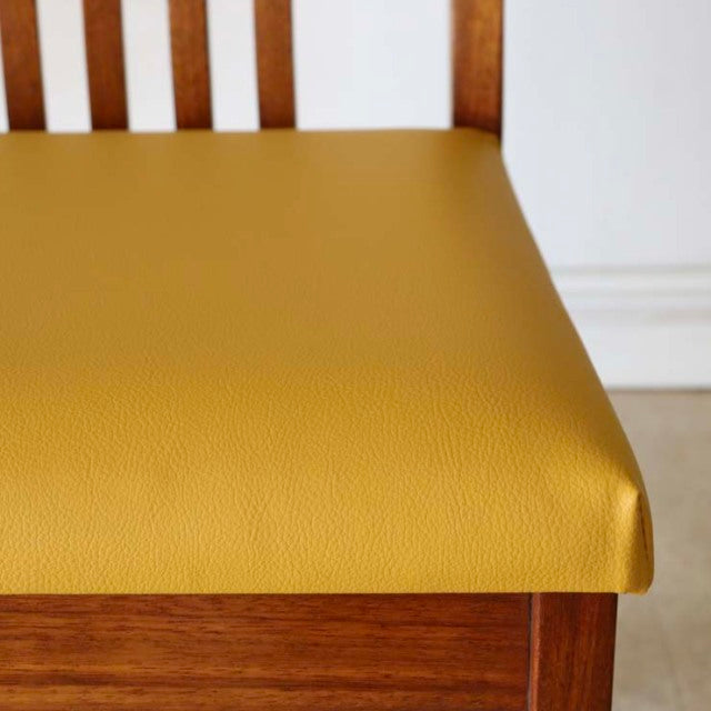Vintage British mid-century teak dining chair with bright yellow leather seat and slatted backrest, showcasing warm wood.