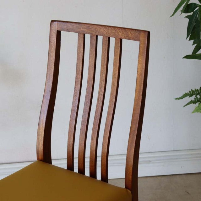 Mid-century British teak dining chair with curved slatted back and yellow seat, vintage condition.