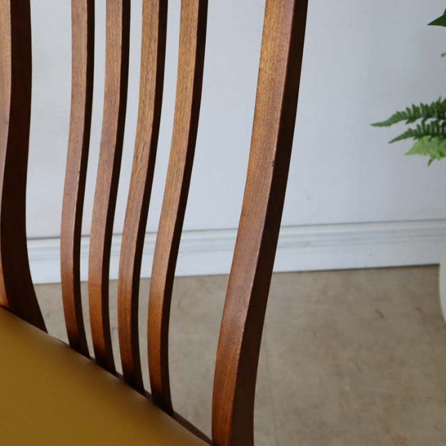 Mid-century British vintage teak dining chair with curved vertical slats and mustard yellow seat cushion, showcasing warm.