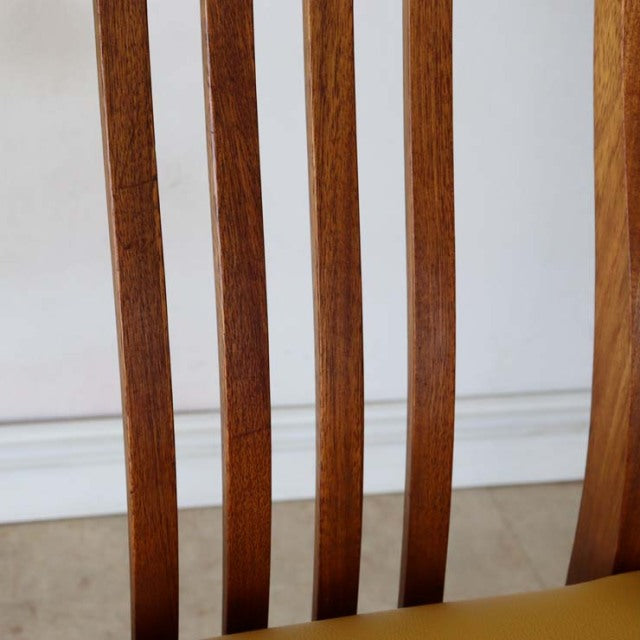 Mid-century British vintage teak dining chair with vertical slatted back and yellow seat cushion.