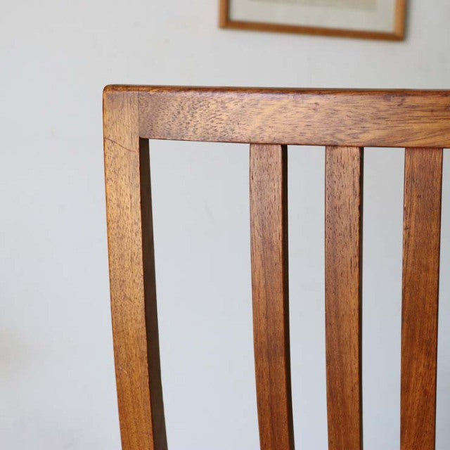 Mid-century British vintage teak dining chair backrest with vertical slats and warm wood grain.