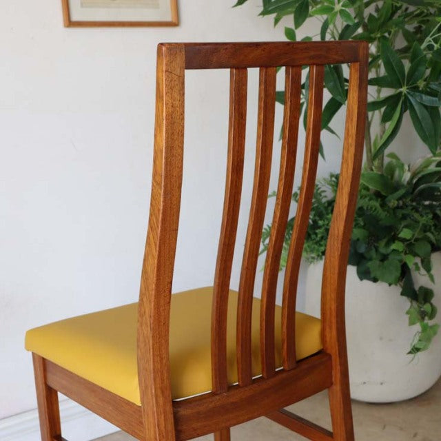 Vintage British mid-century teak dining chair with tall slatted back and yellow upholstered seat.