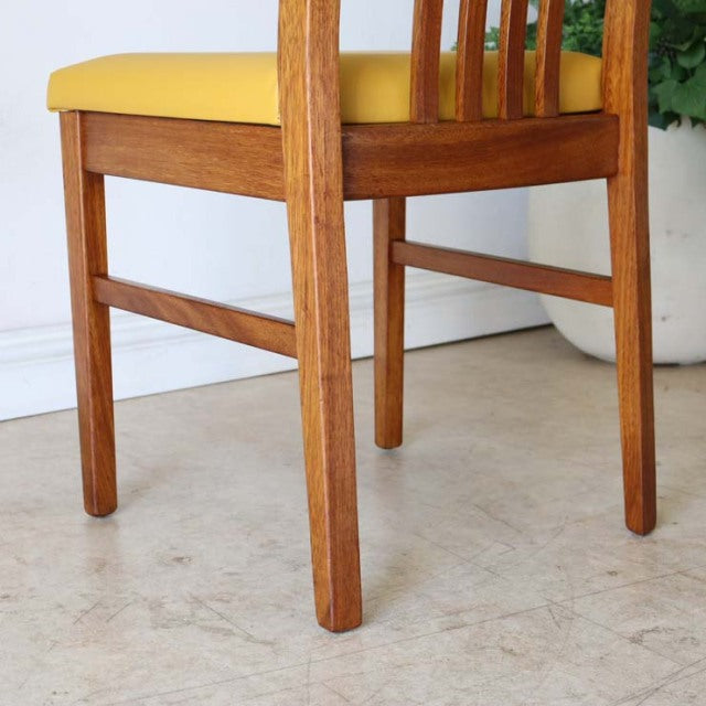 Mid-century British vintage teak dining chair with yellow upholstered seat and straight legs.