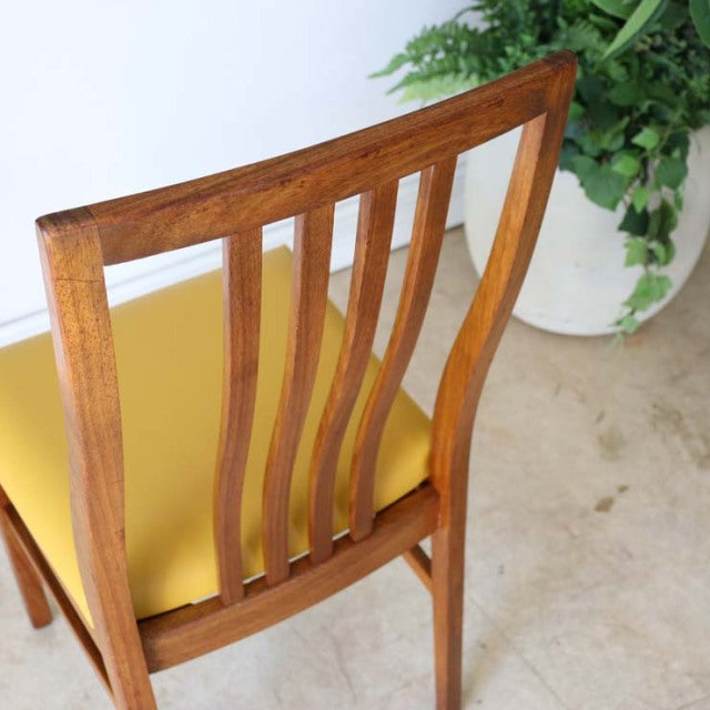 Mid-century British vintage teak dining chair with curved slat back and yellow upholstered seat.