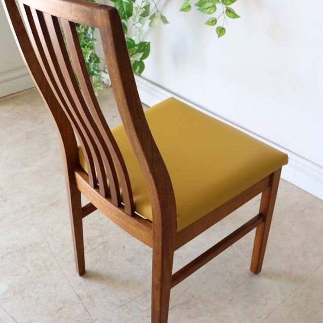 Vintage British mid-century teak dining chair with curved slatted back and yellow upholstered seat.