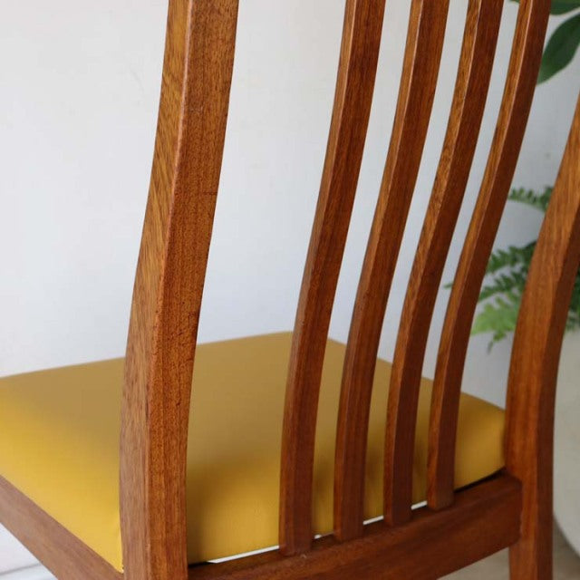Vintage teak mid-century British dining chair with curved slatted back and yellow seat cushion.