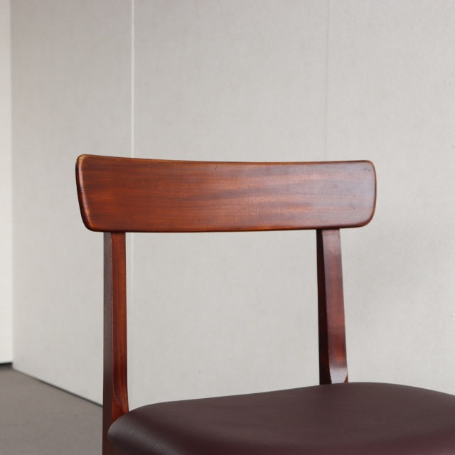 Mid-century British vintage teak dining chair with curved wooden backrest and dark leather seat upholstered, sleek tapered.