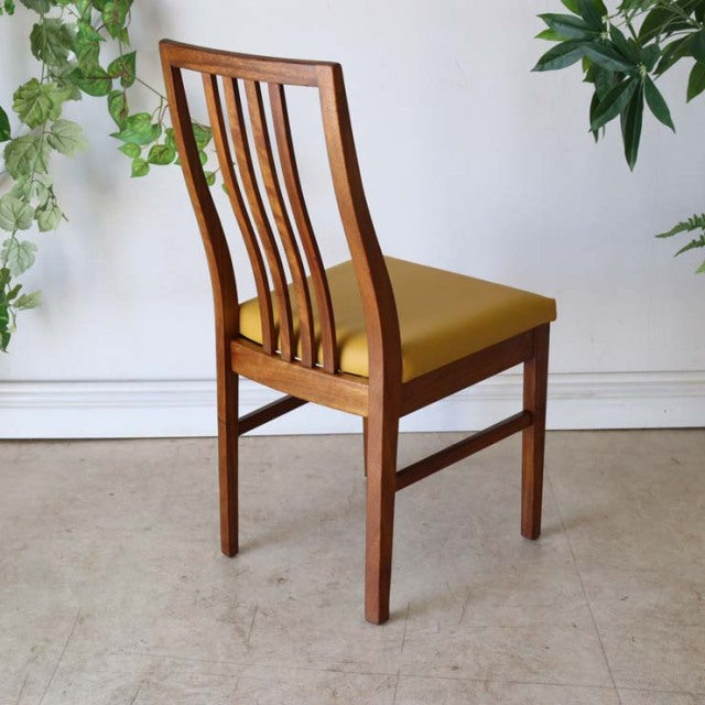 Vintage British mid-century teak dining chair with mustard yellow upholstered seat and slatted backrest.