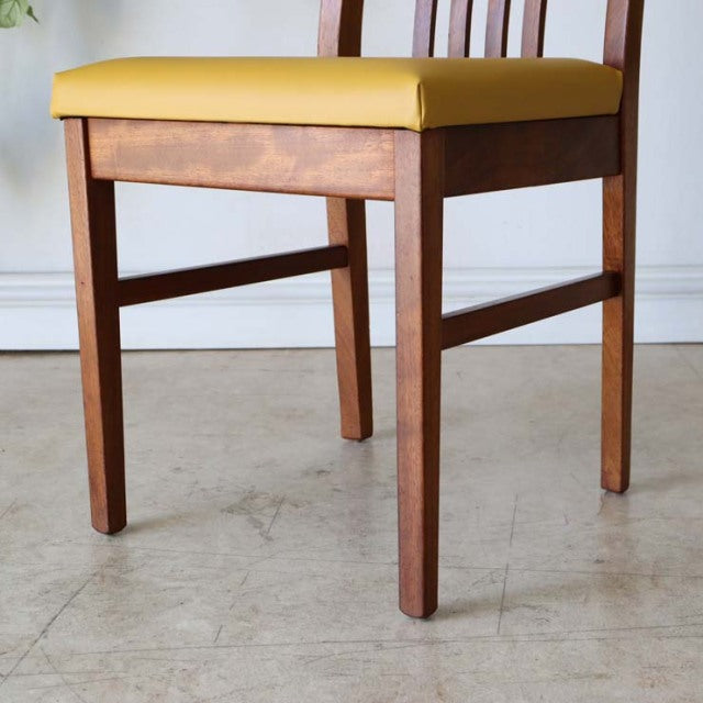 Mid-century British vintage teak dining chair with yellow upholstered seat and slender legs.