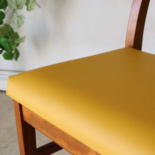 Mid-century vintage teak dining chair with bright yellow seat cushion and curved British-style backrest.