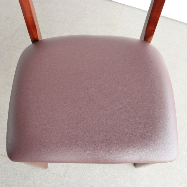 Mid-century British vintage teak dining chair with smooth brown leather seat and visible wood grain legs.