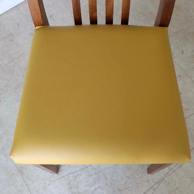 Vintage British mid-century teak dining chair with smooth yellow seat and vertical slat backrest.