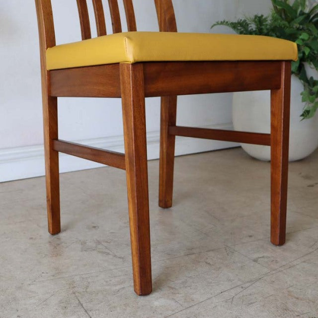 Mid-century vintage British teak dining chair with vibrant yellow cushioned seat and sleek, straight legs.