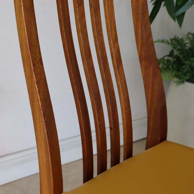 Vintage teak dining chair with tall, slender slatted back and smooth yellow seat, British mid-century style.