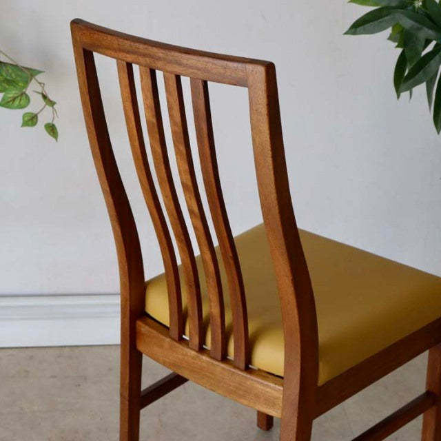 Set of four vintage mid-century teak dining chairs with yellow upholstered seats, British-Danish design, curved slatted.