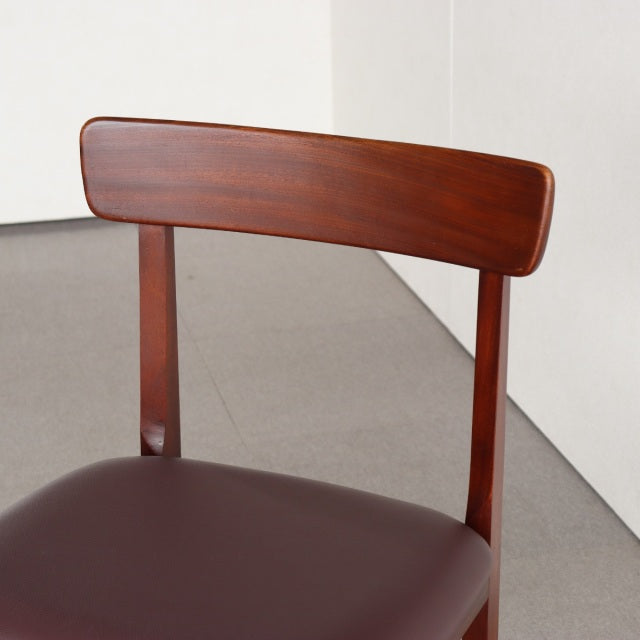 Mid-century British vintage dining chair in teak with curved backrest and dark leather seat.