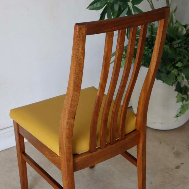 Mid-century British vintage teak dining chair with yellow upholstered seat, curved slat backrest, and tapered legs in good.