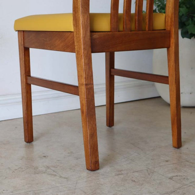 Mid-century British vintage teak dining chair with yellow upholstered seat and visible wood grain.
