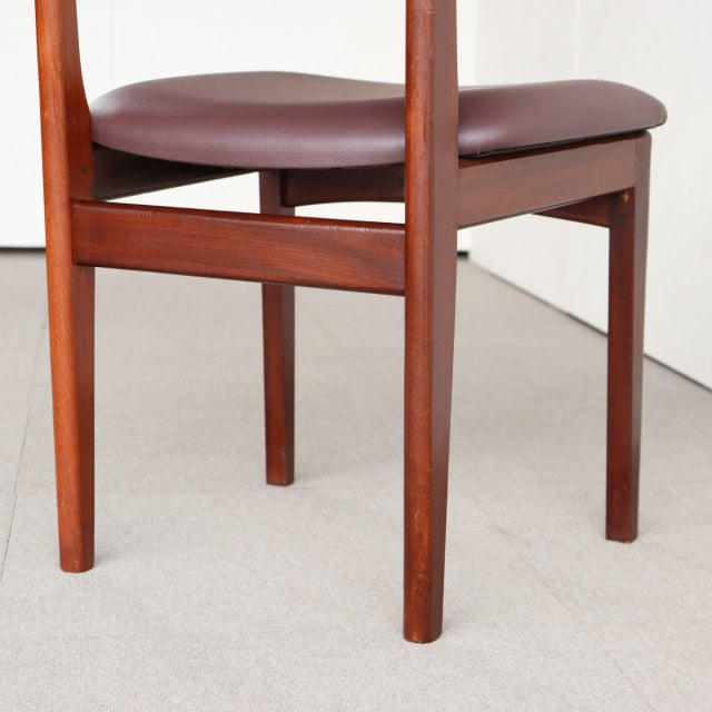 Mid-century British vintage dining chair in teak with rounded legs and burgundy leather seat cushion.