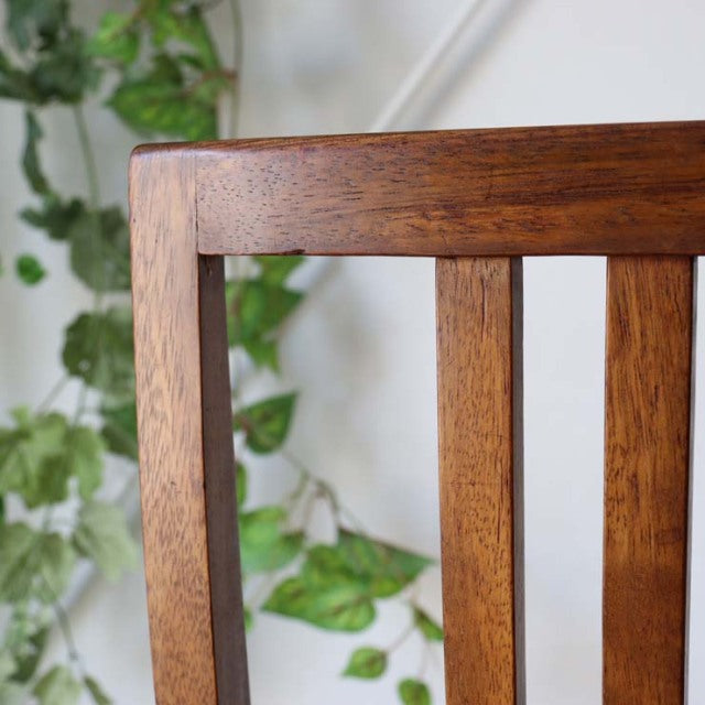 Mid-century British vintage teak dining chair backrest with rich wood grain and vertical slats.