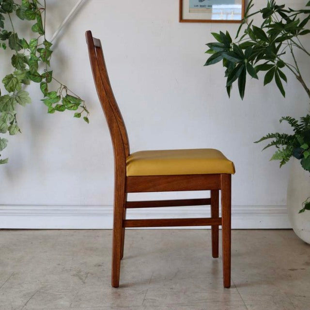 Mid-century British vintage teak dining chair with sleek wood grain and mustard yellow upholstered seat.