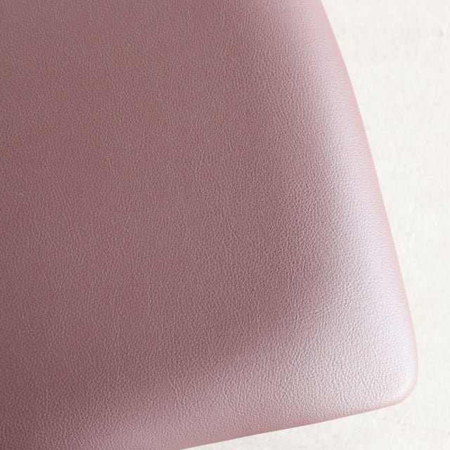 Close-up of warm brown leather seat cushion with fine grain texture on vintage mid-century teak dining chair.