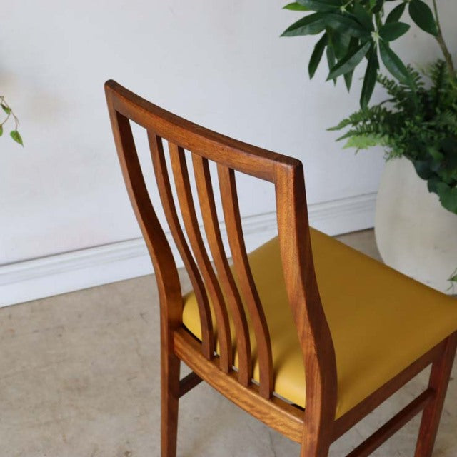 Vintage British mid-century teak dining chair with vertical slatted back and mustard yellow seat cushion.