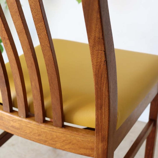 Mid-century British vintage teak dining chair with curved slatted backrest and yellow upholstered seat.