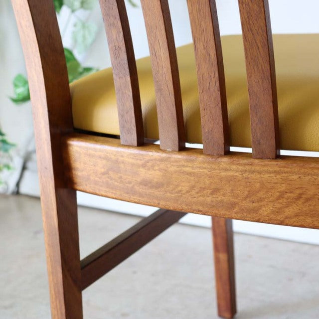 Mid-century British vintage teak dining chair with vertical slat back and yellow upholstered seat, showcasing warm wood.