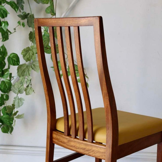 Mid-century British vintage teak dining chair with curved slatted back and yellow upholstered seat.