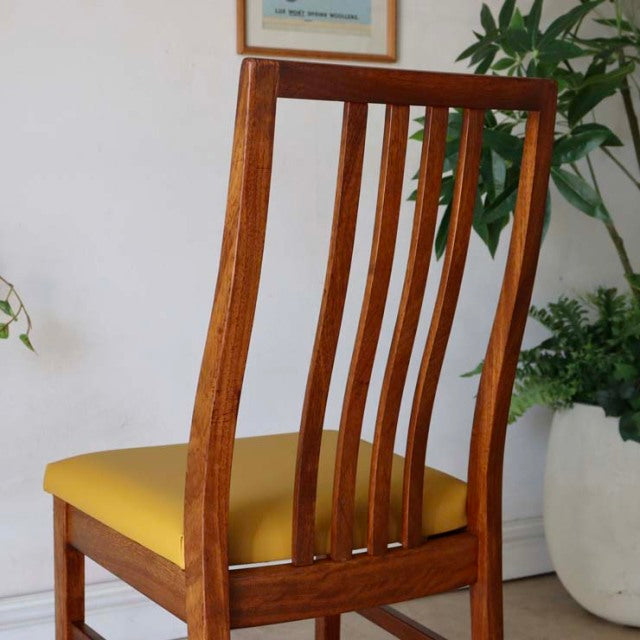 Mid-century British vintage teak dining chair with curved slatted back and yellow upholstered seat.