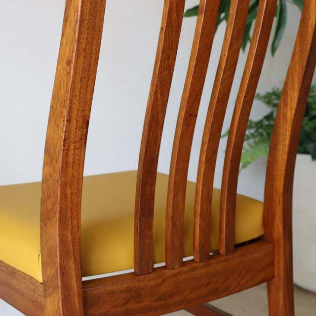 Mid-century British vintage teak dining chair with yellow upholstered seat, slatted curved backrest, and tapered legs in.