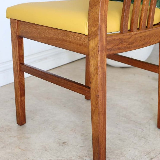 Mid-century British teak dining chair with yellow upholstered seat, visible wood grain and sturdy square legs.