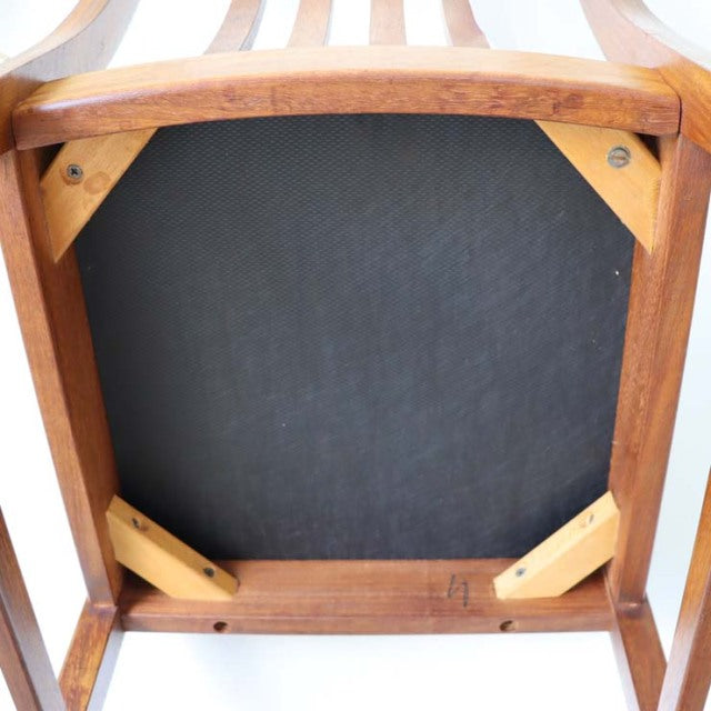 Vintage teak dining chair underside showing sturdy wooden frame, reinforced corners, and dark seat backing, British.