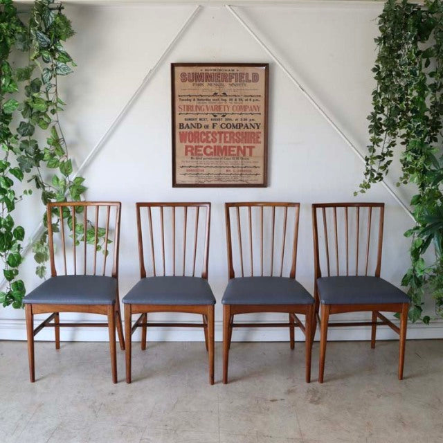 Set of four vintage mid-century British teak dining chairs with sharp backs, vertical slats, and dark gray upholstered.